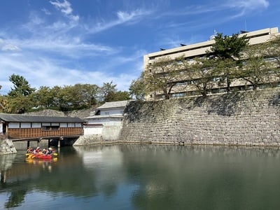 廊下橋下をくぐる遊覧ボートと福井城址(県庁・県警察本部)